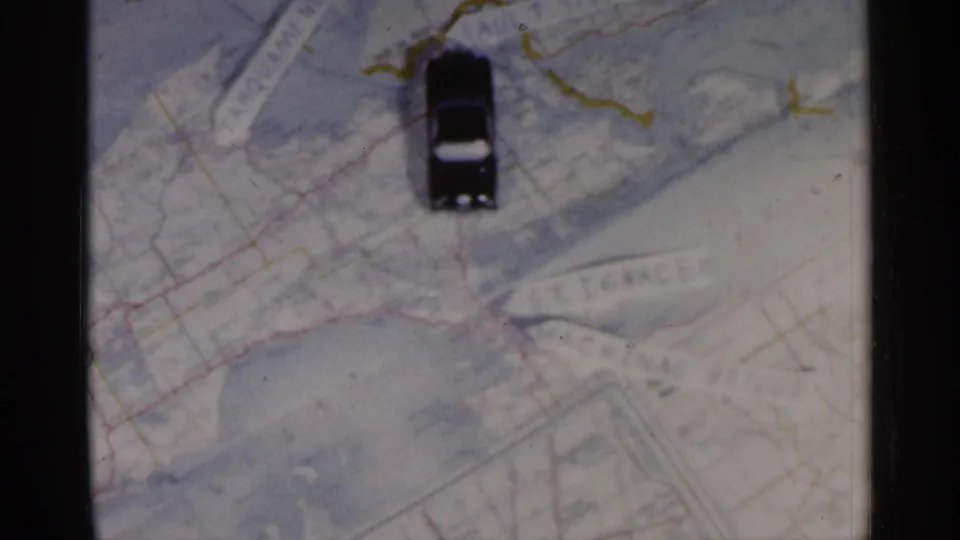 A final 8mm frame shows the black toy car standing vertically on the map, with colored road lines and partial printed text around it.