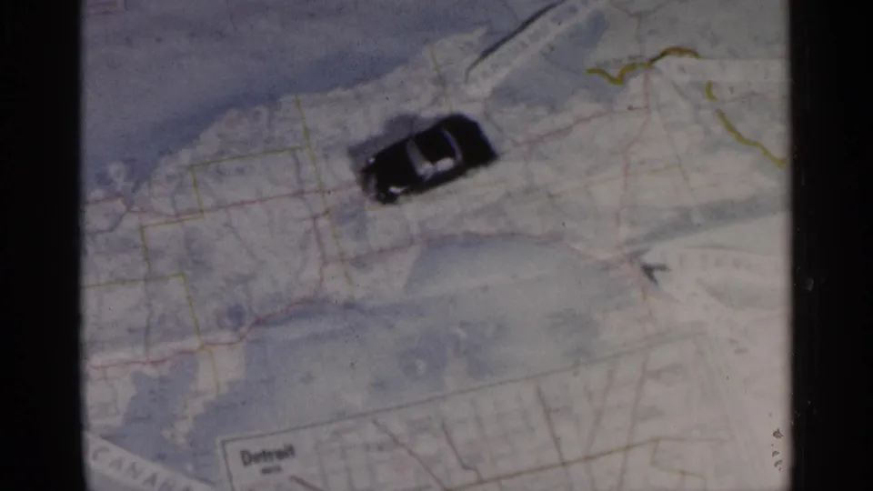 The toy car appears near the Detroit area on the Michigan map, with printed labels, roads, and drawn route lines visible.