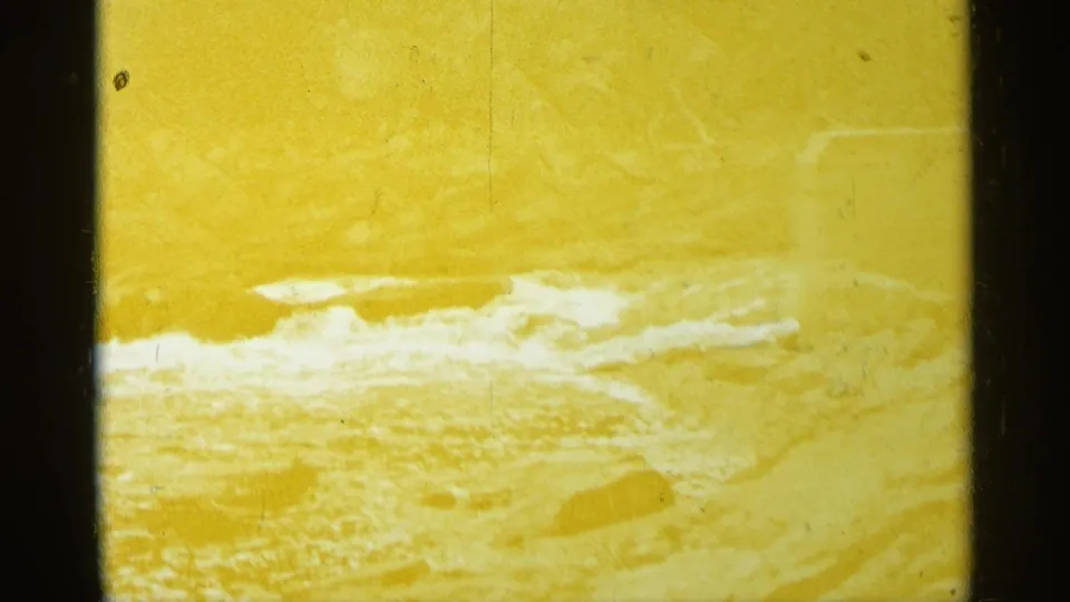 1960 Michigan 8mm frame showing flooded white water or rapids through a yellow color cast and soft home-movie exposure.