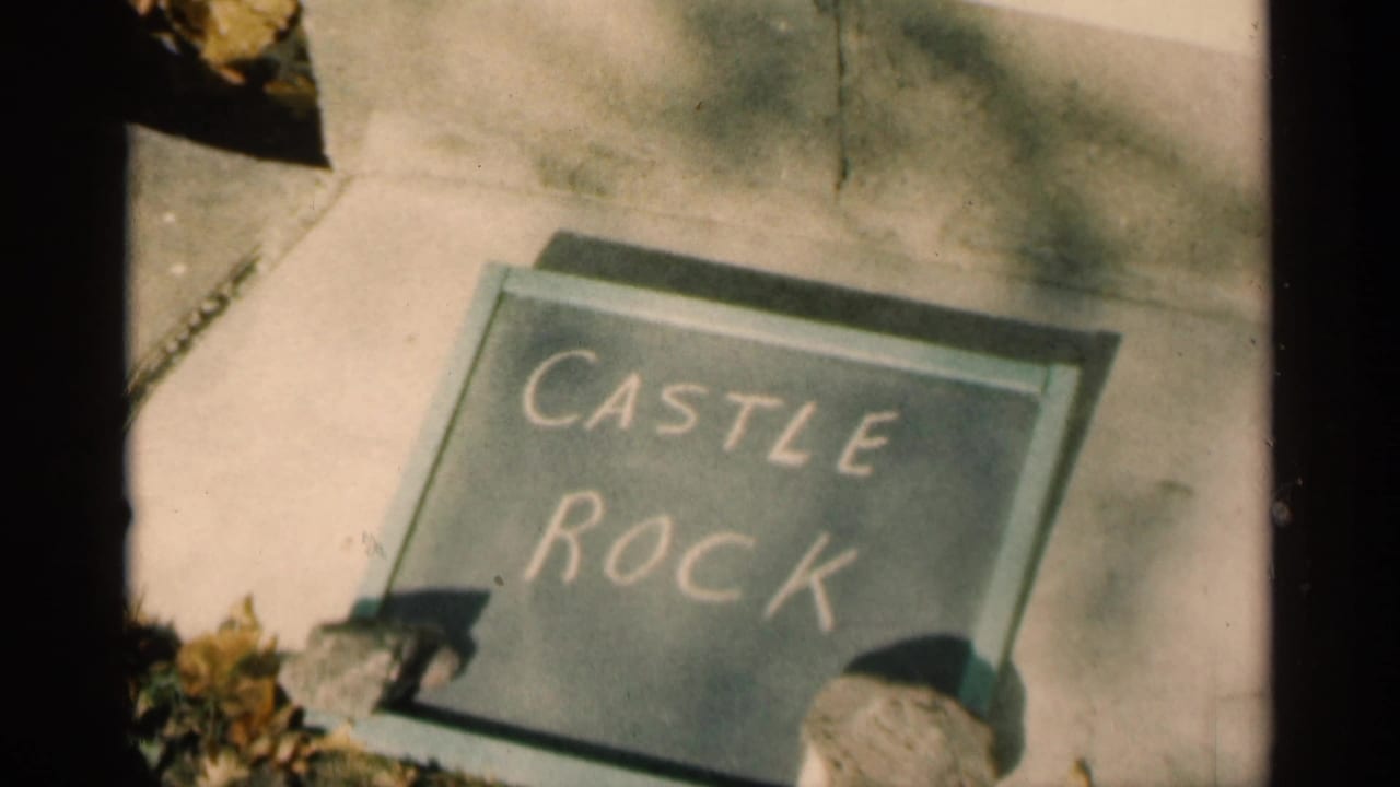 Chalkboard on pavement reads Castle Rock, with sidewalk, leaves, and partial objects at the edges.