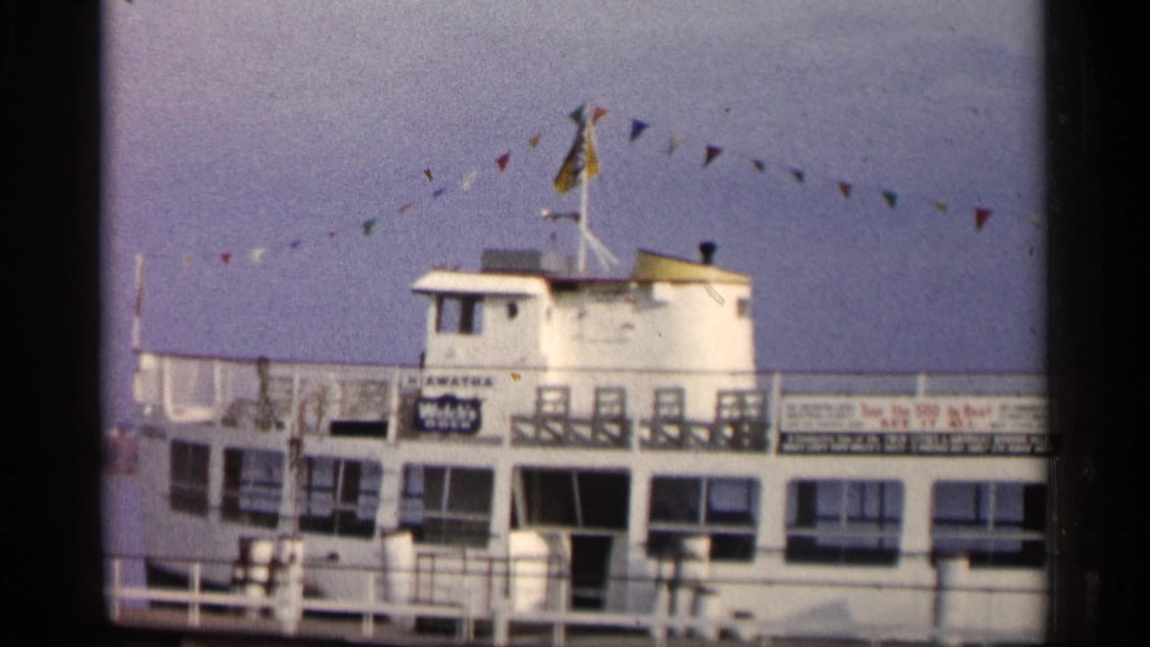 White passenger boat at a dock with colorful bunting above the deck.