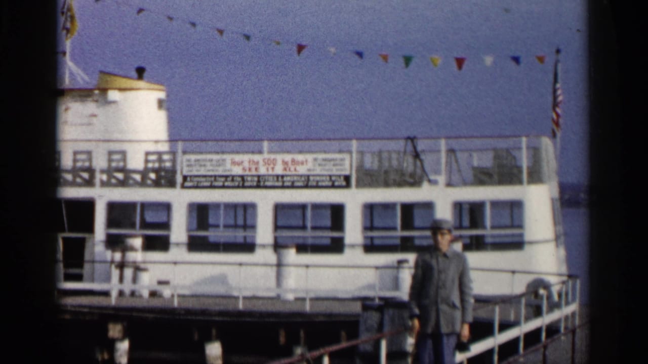 Man standing on a dock beside a white tour boat with flags above.