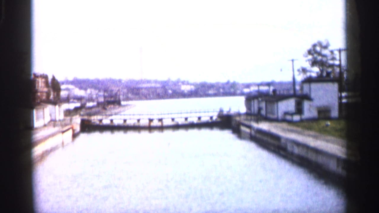 Canal or lock channel with a low barrier, small building, and utility poles.