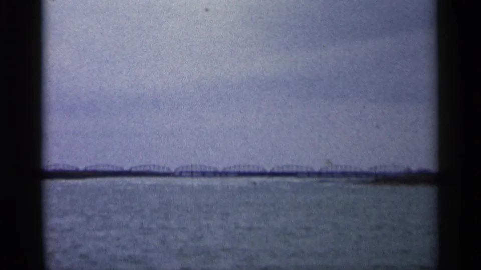 The final frame holds on a soft, grainy view of open water and a distant bridge, consistent with the clip's Michigan lakeside setting.