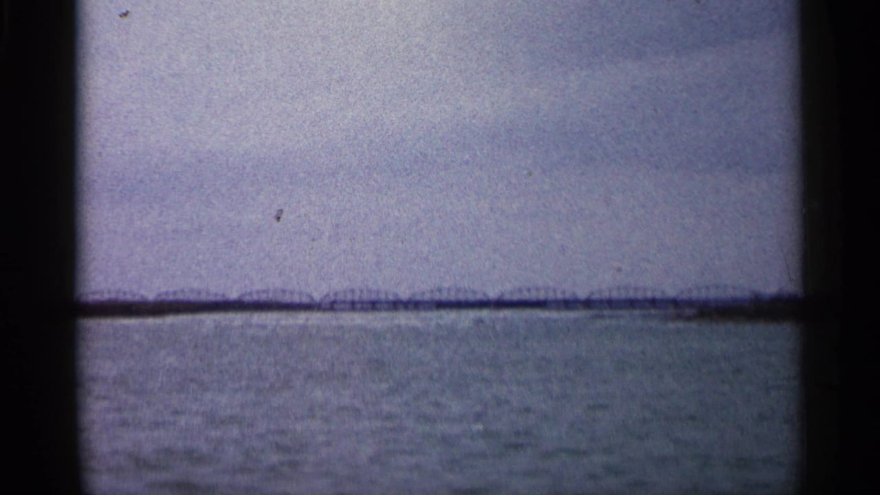 Similar wide water view with the horizon and distant bridge or shoreline visible through the film gate.