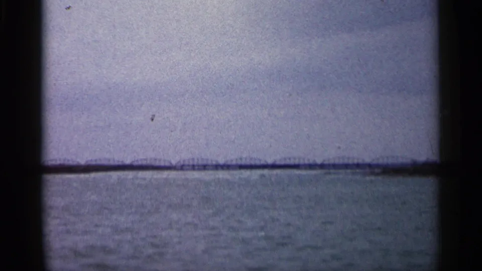 Wide 8mm view in Michigan showing water, a low distant bridge or shoreline line, and overcast sky framed by dark gate edges.