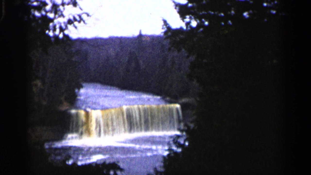 Waterfall spilling over a ledge with trees framing the river.