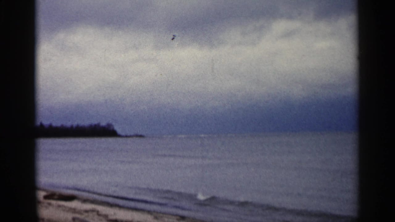 Lake horizon and cloudy sky with a dark shoreline point at left.