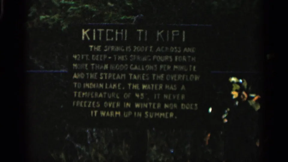 Visitor-shot 8mm view of the Kitchi Ti Kipi plaque in Michigan, with readable spring measurements and a small object at right.