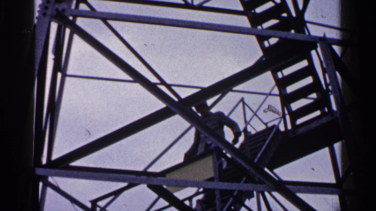 Silhouetted man continues up stairs within a metal tower framework.