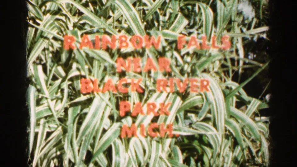 Michigan home-movie title card over tall grass reading Rainbow Falls near Black River Park Mich.