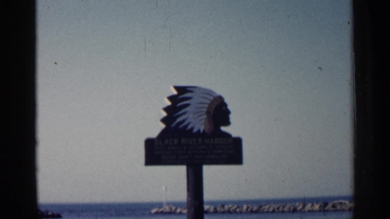 Black River Harbor sign with chief silhouette beside water and a rocky breakwater.