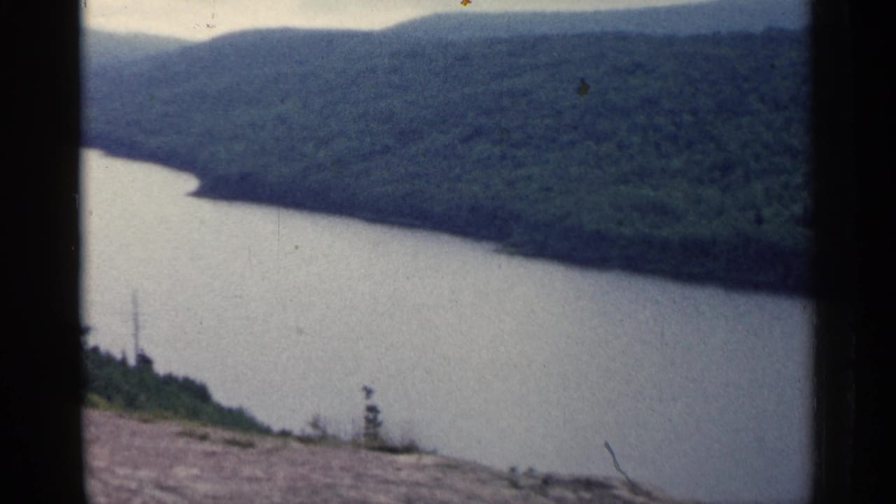 River and wooded valley viewed from above, with hazy hills and film scratches near the frame edge.