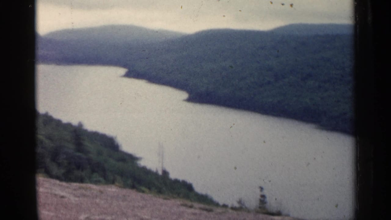 Curving water and wooded hills seen through visible 8mm frame borders.