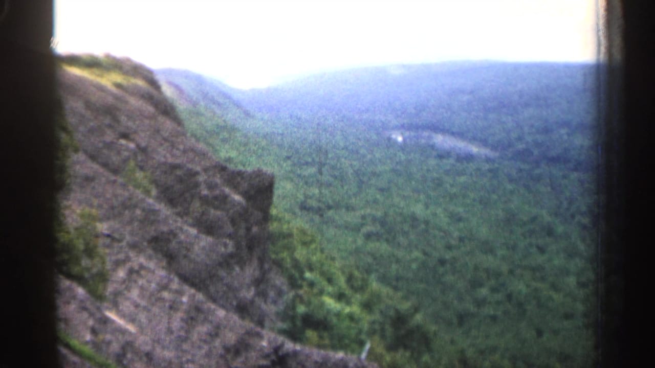 Handheld 8mm scenic view of a rocky overlook and forested Michigan valley, with film borders visible.