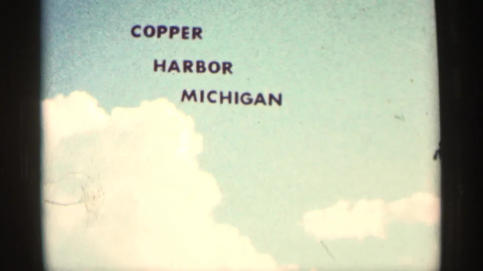 Location title card reading Copper Harbor Michigan, shown on faded 8mm home-movie film.