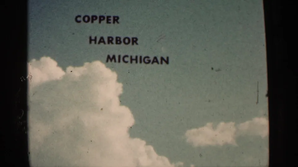 Faded 8mm title card for Copper Harbor Michigan with clouds below the printed lettering.