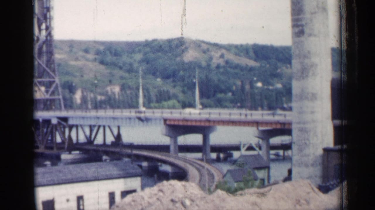 Bridge over water with hills behind it and rail tracks curving below.