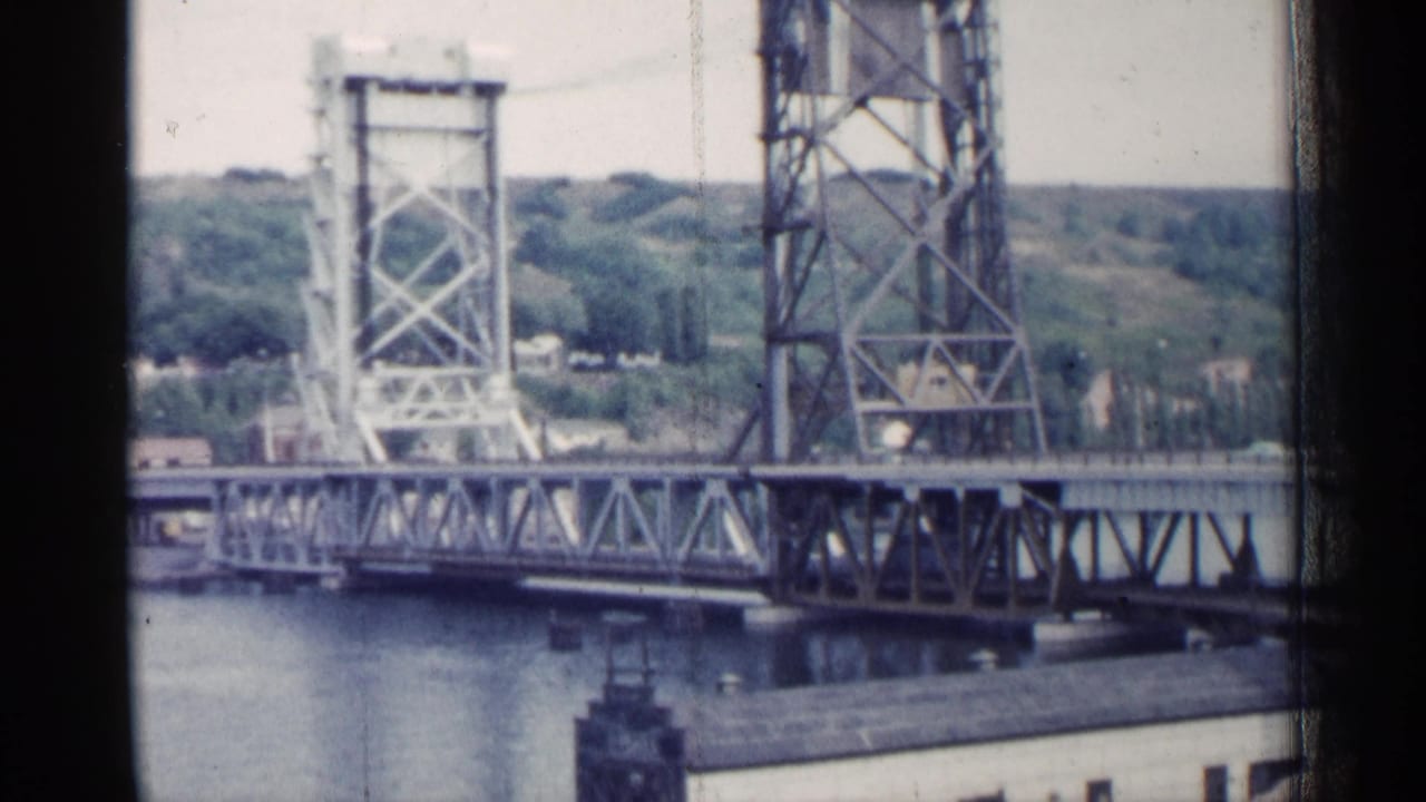 1960 Michigan home-movie view of a steel drawbridge, water surface, distant trees, and low shoreline structures.