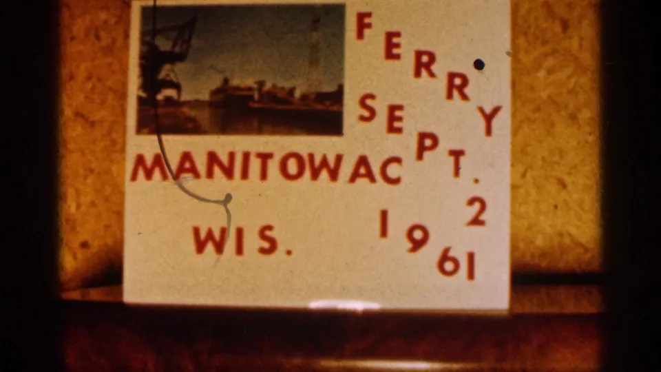 Close view of the homemade ferry title card, with red cutout-style letters and numerals against a warm indoor backdrop.