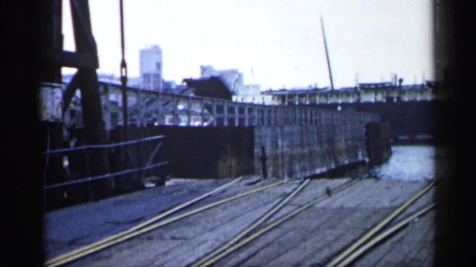 1960 Michigan harbor frame with dock rails, bridge machinery, water channel, and industrial waterfront structures.