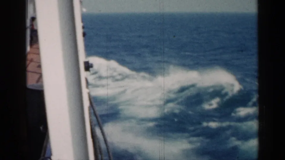 Foaming ship wake fills the water beside a white vessel rail, continuing the 1960 Michigan ferry travel view.