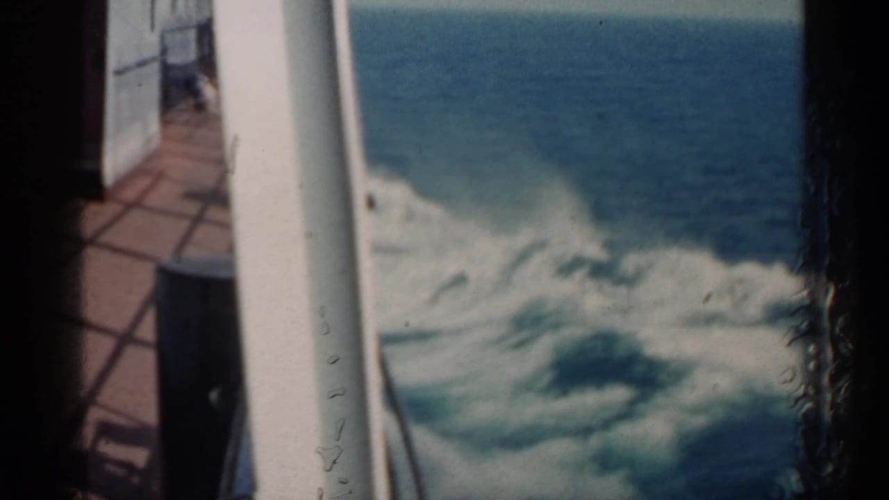 Waves churn beside a boat deck and white railing.