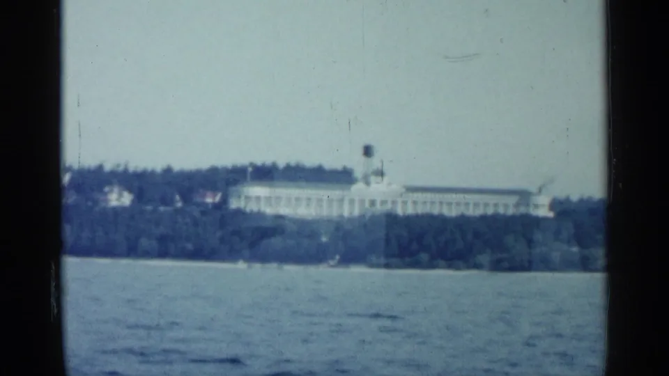 Distant shoreline view in Michigan showing a large white building above trees, filmed across open water.