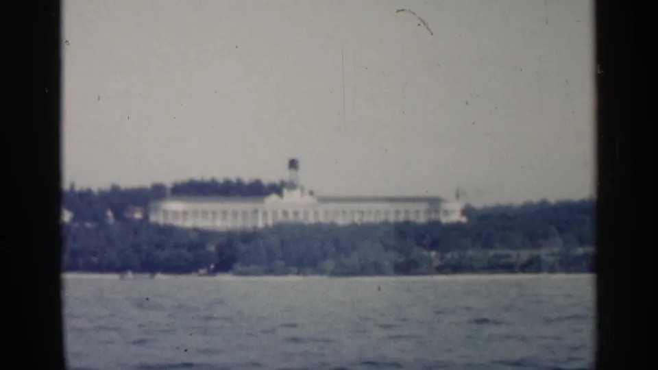 End frame of the Michigan boat view, with a long white building across rippling water.