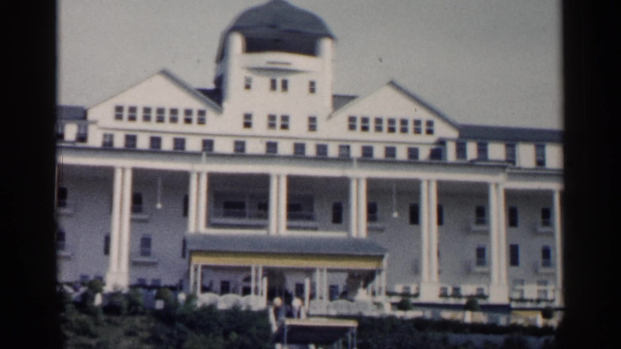1960 Michigan resort exterior seen from below, showing the central dome, long columned porch, entrance canopy, landscaping, and distant visitors.