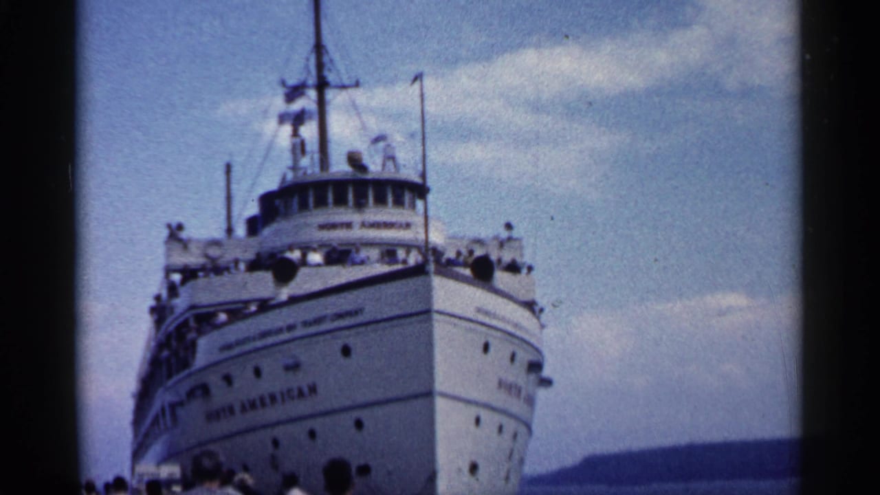 White passenger ship bow seen from dock level under a blue sky.