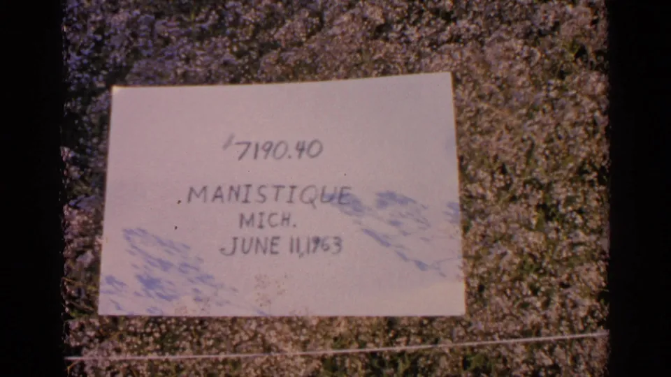 Another close view of the handwritten Manistique, Michigan label, with date text and faded blue shadowing visible on the paper.