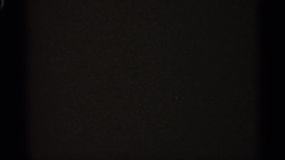A mostly dark 8mm frame with visible grain and only faint tonal variation, likely from the end or unexposed portion of the reel.