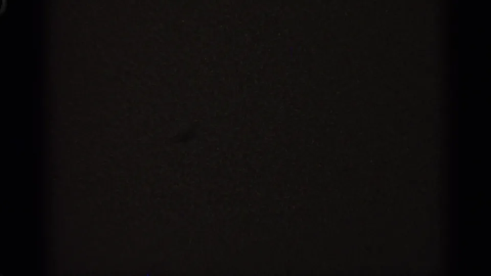 A dark end-of-reel style frame showing subtle film grain and uneven exposure, with no identifiable people or objects visible.