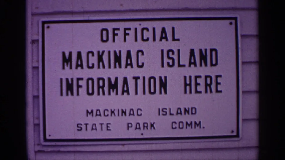 Mackinac Island information sign mounted on siding, identifying the State Park Commission below the main text.