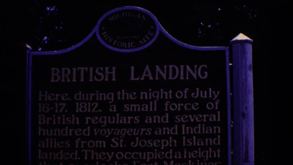 1960 Michigan 8mm frame showing a dim, purple-tinted British Landing historic marker among trees.