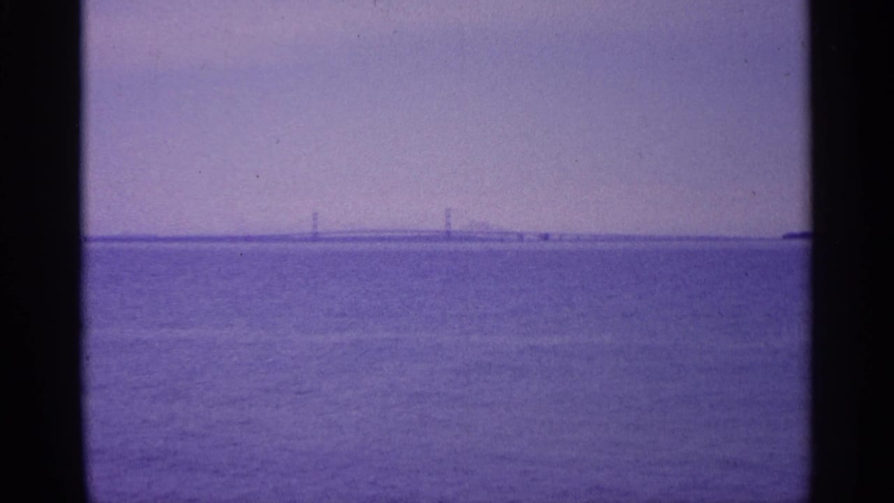 Distant bridge spans the horizon over a wide body of water.
