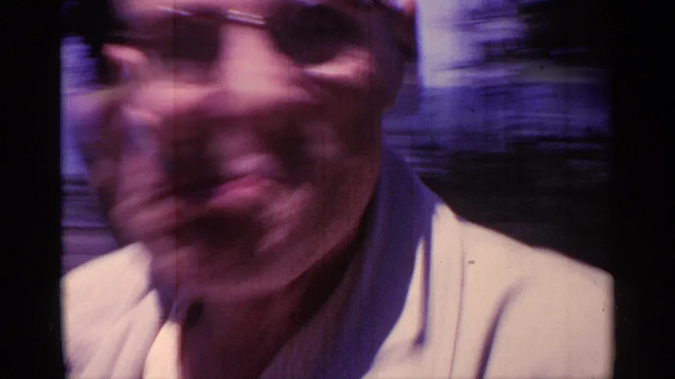 A very close, motion-blurred home-movie frame shows the man's face and light jacket as he passes the camera.