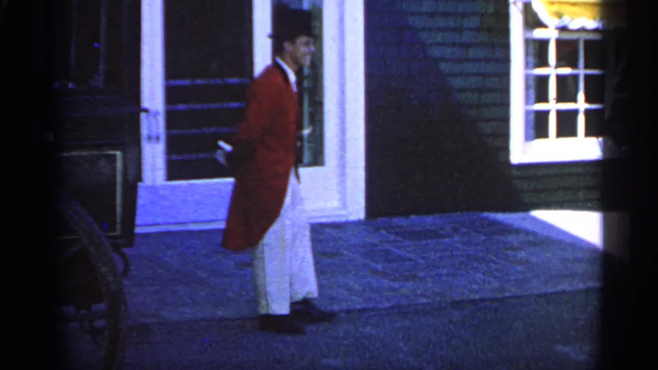 Near the end of the 1960 Michigan clip, the red-tailcoated man passes the white-trimmed entrance in darker blue-toned light.