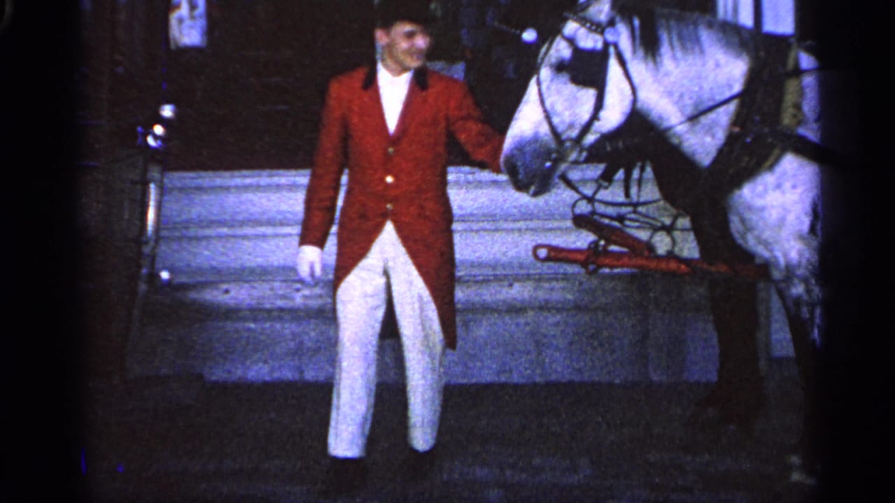 The 1960 Michigan home-movie frame shows the costumed man beside the white horse, with harness hardware visible.