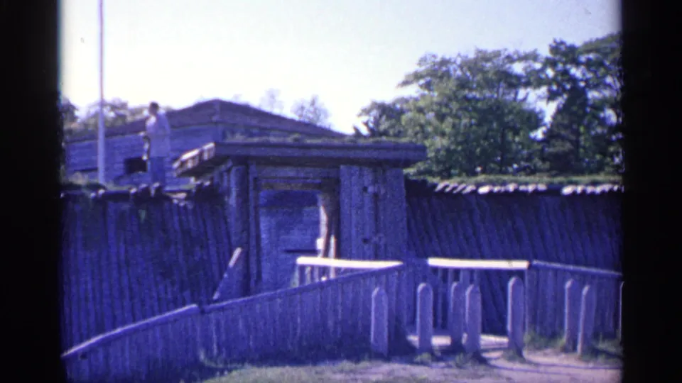 1960 Michigan 8mm frame centered on the wooden ramp, railings, and fort structure, with leafy trees behind it.