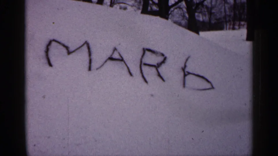 The final frame holds on MARK written in snow, with the 8mm frame edge and winter yard background visible.