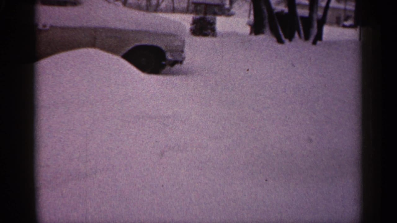 Snow-covered car partly visible beside deep snow in a winter yard.