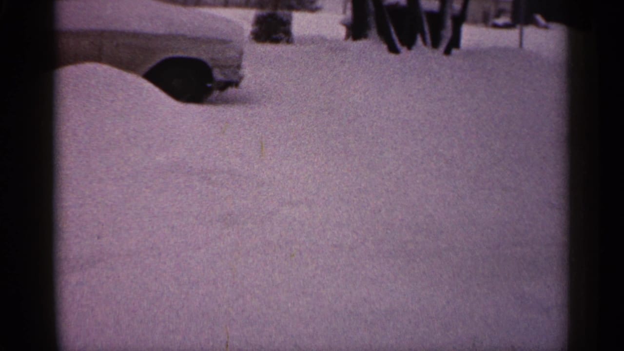 Deep snow fills the foreground with part of a car visible at left.