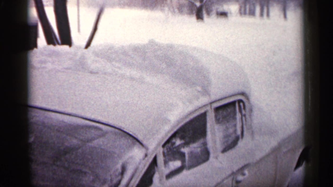 1961 Minnesota 8mm frame showing a parked older car with roof and windows heavily covered by accumulated snow.