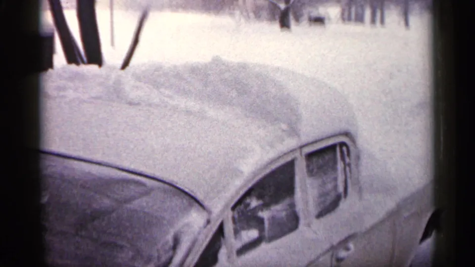 1961 Minnesota 8mm frame showing a parked older car with roof and windows heavily covered by accumulated snow.