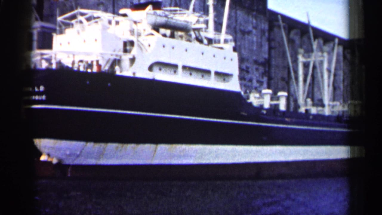 Docked ship's stern and side beside a tall stone or concrete wall.