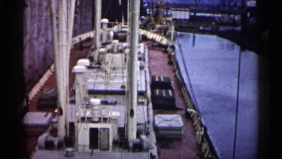 1961 Minnesota 8mm frame showing a high-angle deck view of a docked cargo vessel with rigging and covered deck items.