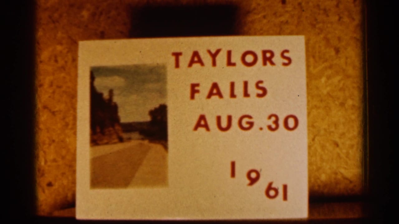 Handwritten 1961 title card for Taylors Falls with red lettering and a small landscape photograph on a warm-toned surface.