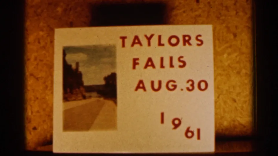 Handwritten 1961 title card for Taylors Falls with red lettering and a small landscape photograph on a warm-toned surface.